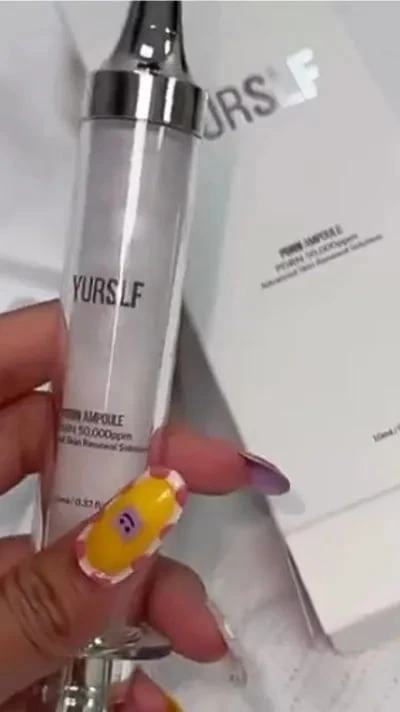 A hand with decorative nails holds a YURS LF ampoule in a syringe-like container.