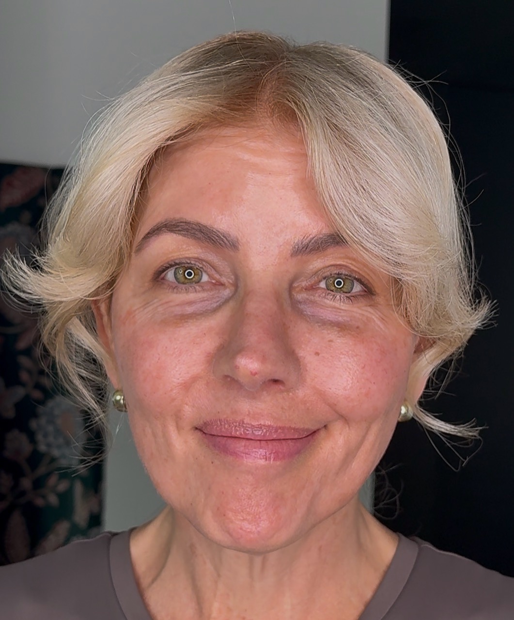 A close-up headshot of a smiling woman with short blonde hair and green eyes looking at the camera.