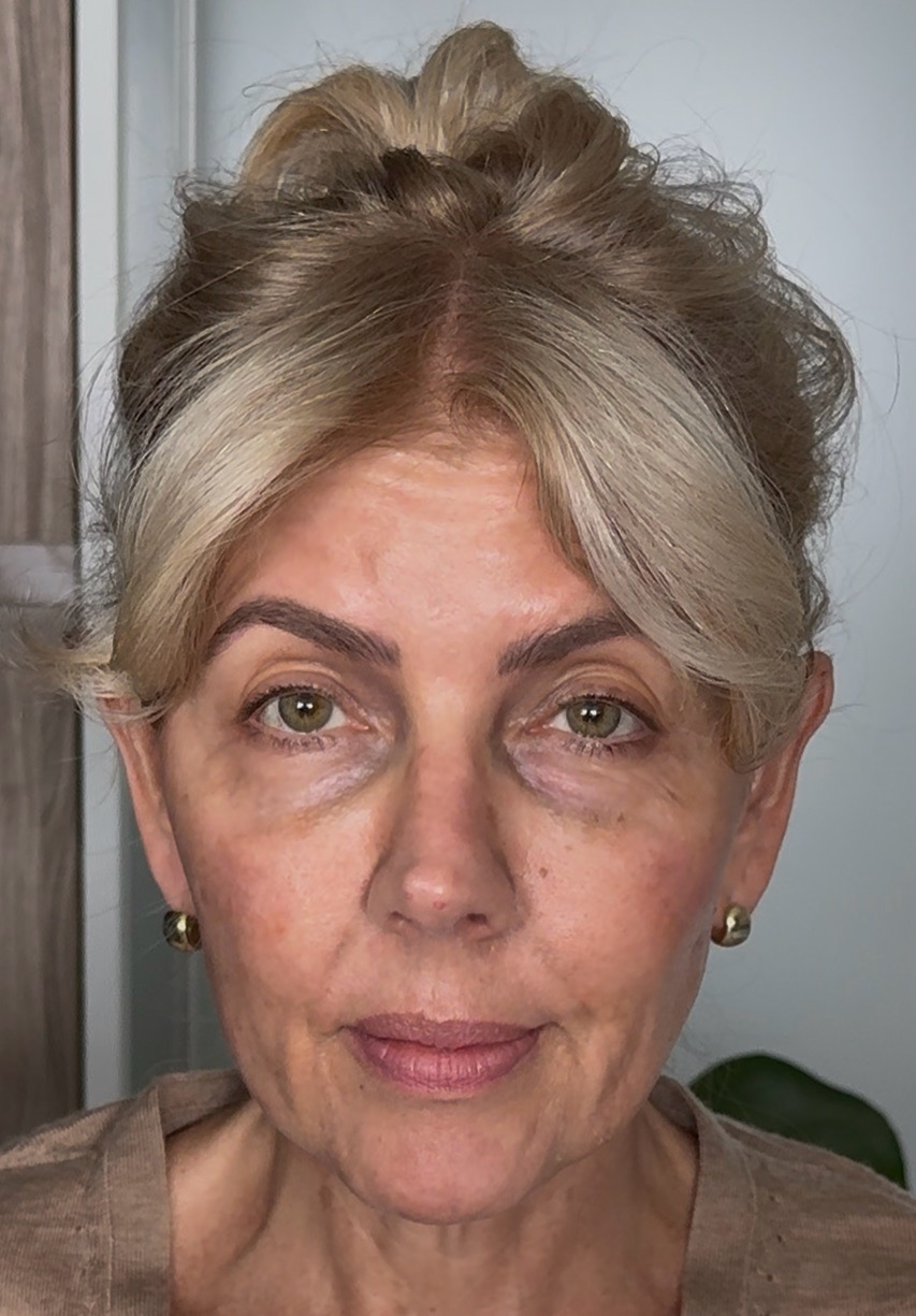 A close-up, front-facing portrait of a woman with blonde hair in an updo and green eyes.