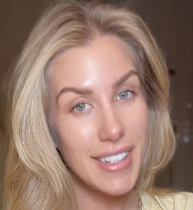 A close-up of a smiling woman with blonde hair and blue eyes looking towards the camera.