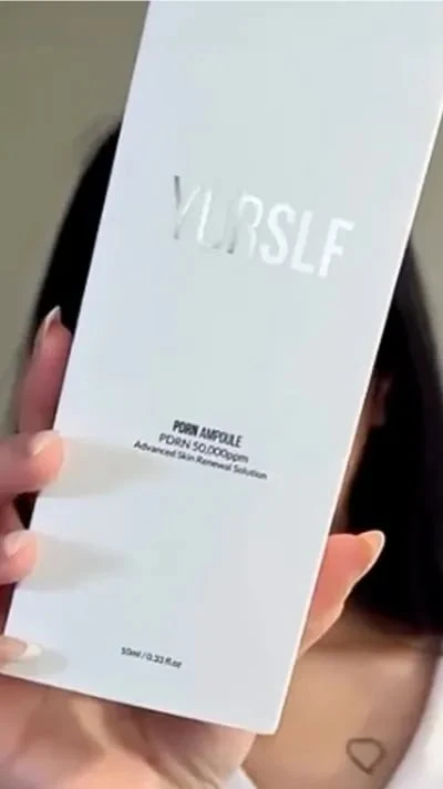 A person holds up the white packaging for YURSLF PDRN Ampoule skin renewal solution.