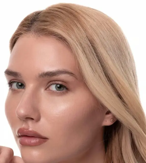 A close-up studio portrait of a woman with blonde hair and light eyes, looking directly at the camera.