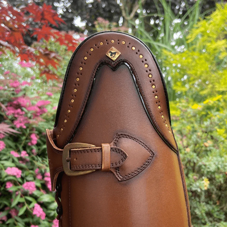 Close-up of a brown leather shoe with decorative stitching and a buckle.