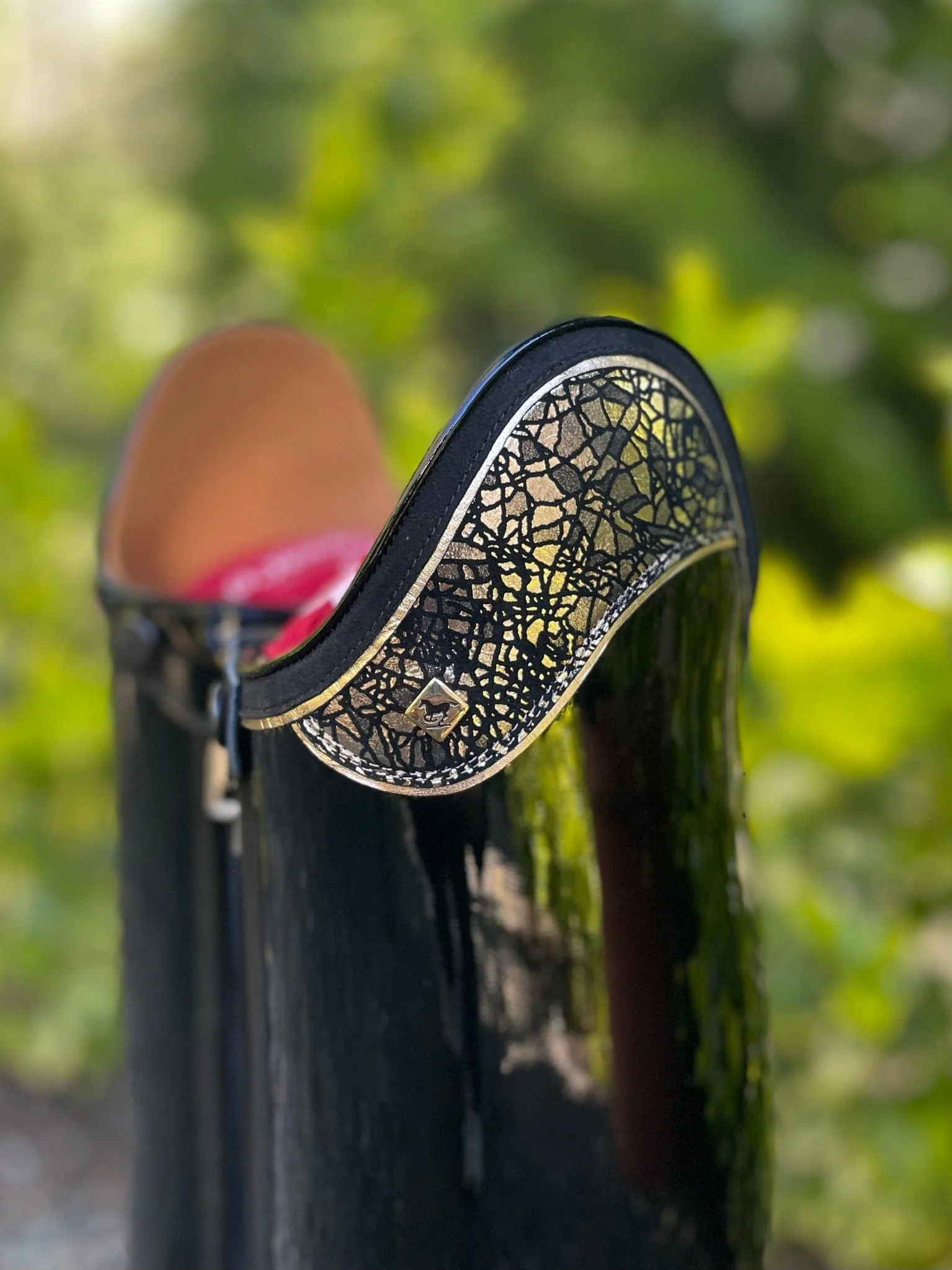 Close-up of a black boot with decorative gold trim.