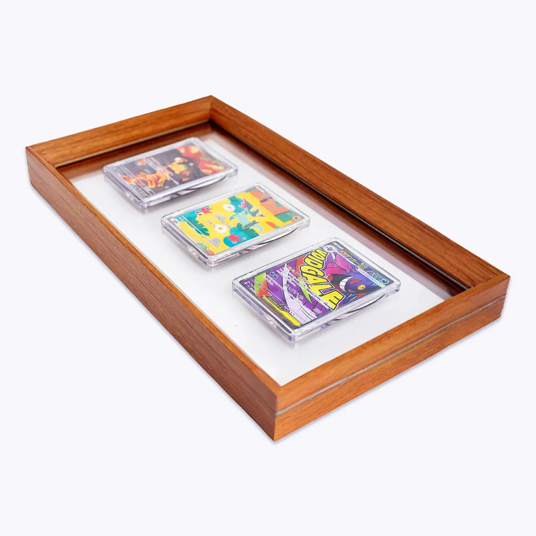 Three trading cards in clear protective cases displayed in a rectangular wooden frame against a white background.