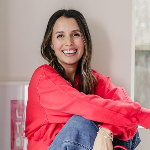Person smiling in a red sweater sitting indoors.