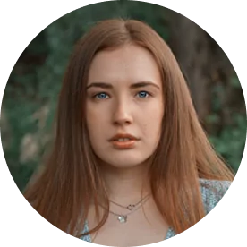 Portrait of a woman with long hair, wearing a necklace, outdoors.
