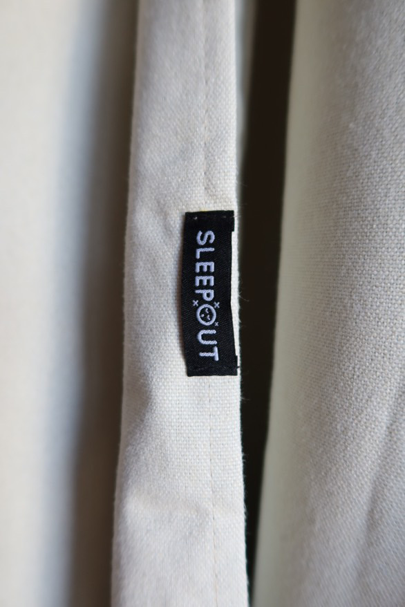 Close-up of a fabric tag labeled 'SLEEPOUT' on a beige textile.