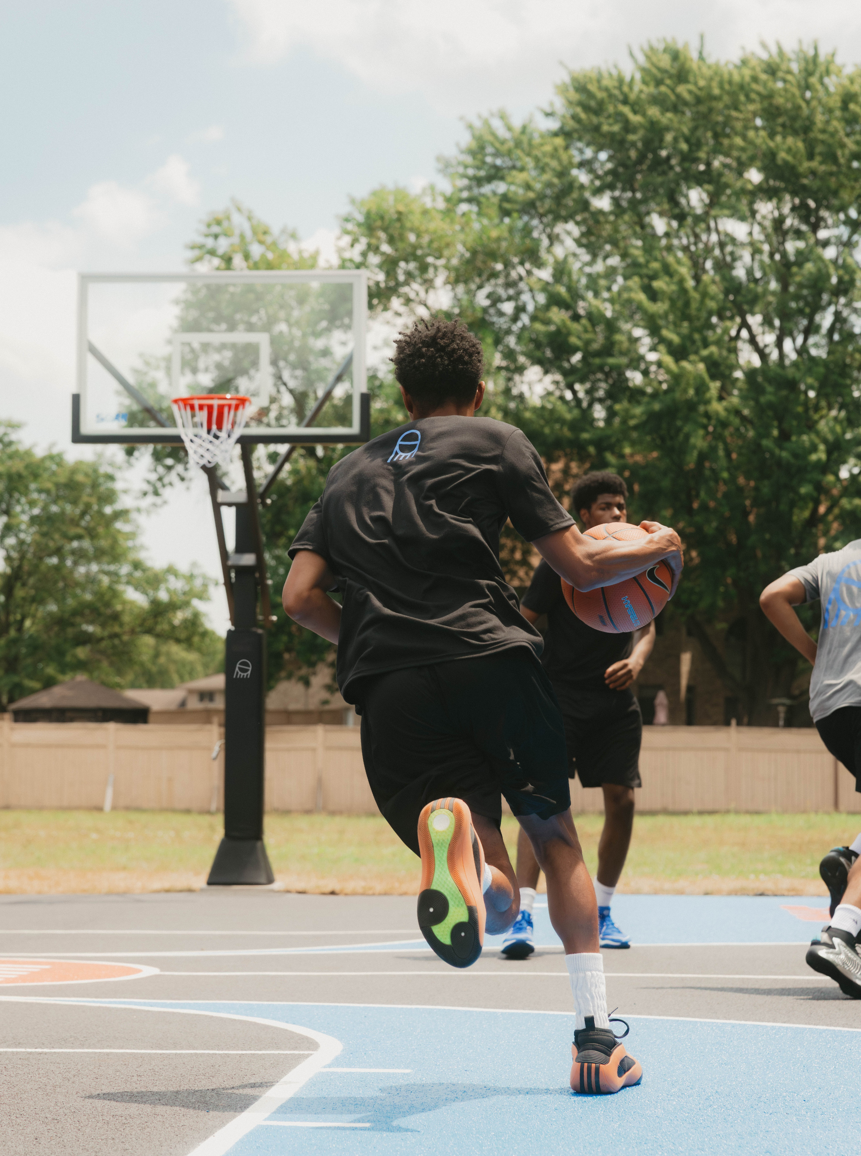 Three people playing basketball on an outdoor court.