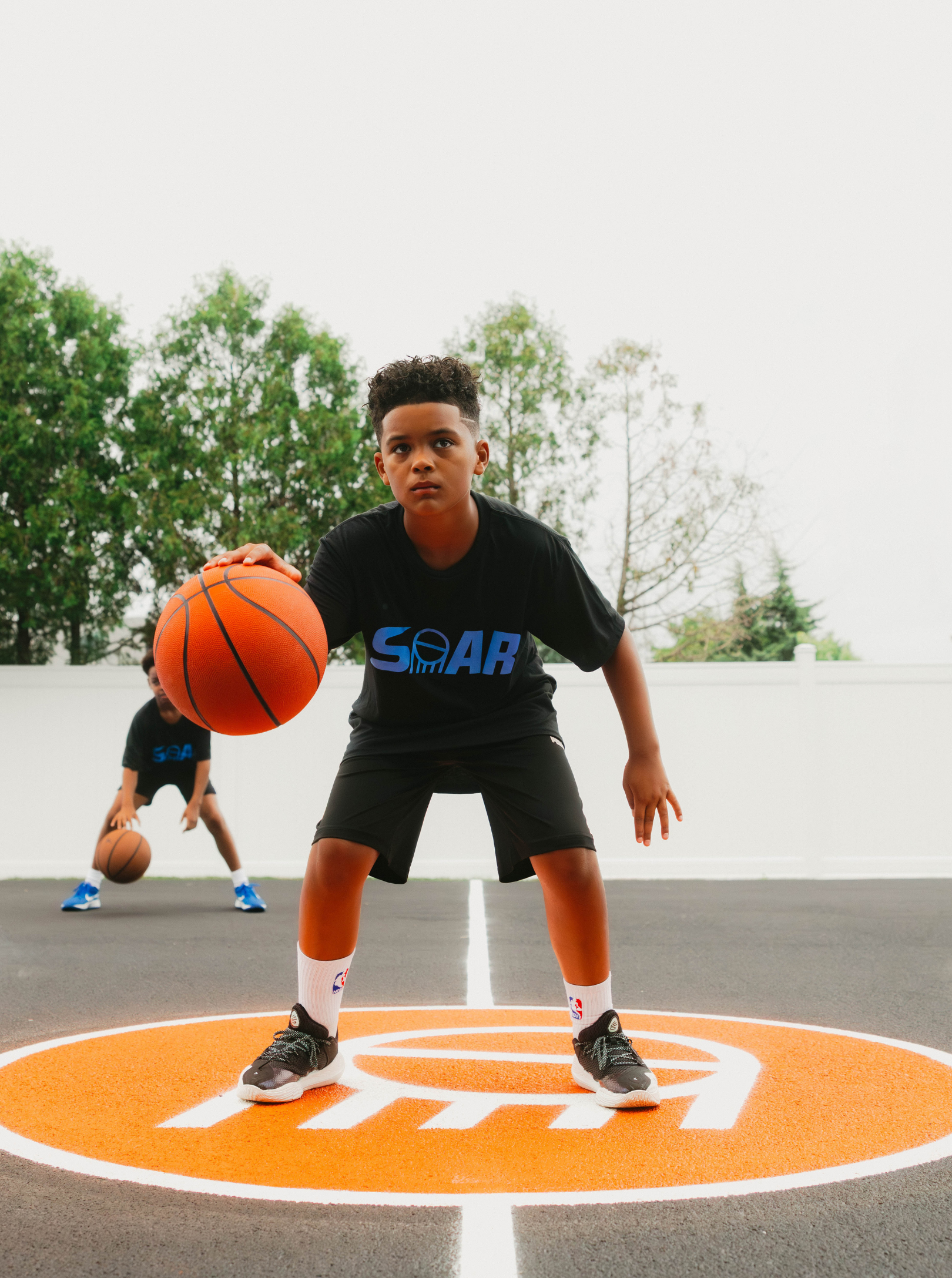 Two boys playing basketball on an outdoor court.