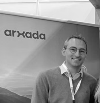 Man smiling in front of an 'arxada' banner.