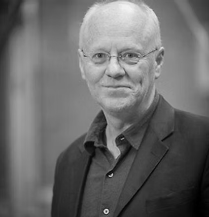 Black and white portrait of an older man in a suit, smiling slightly.