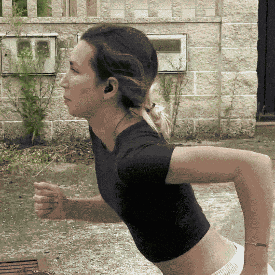 Person running outdoors near a stone wall.