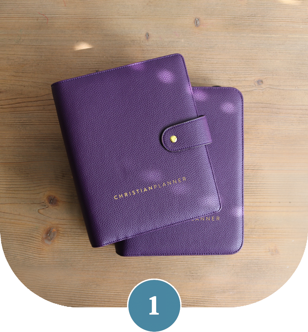 An overhead view of two purple, textured leather binders resting on a wooden surface.