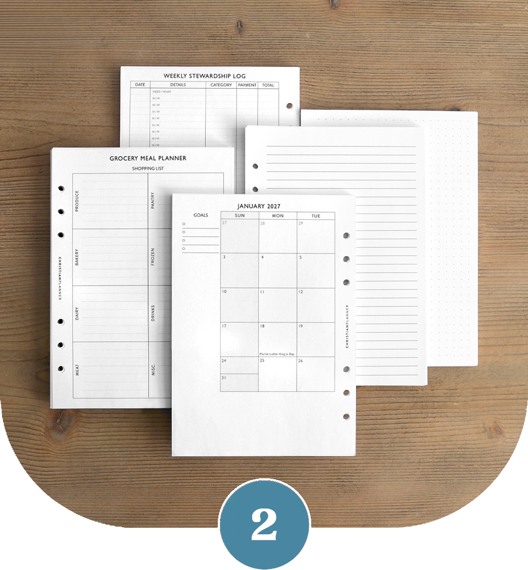 Various planner pages, including a calendar and grocery list, fanned out on a wooden surface.