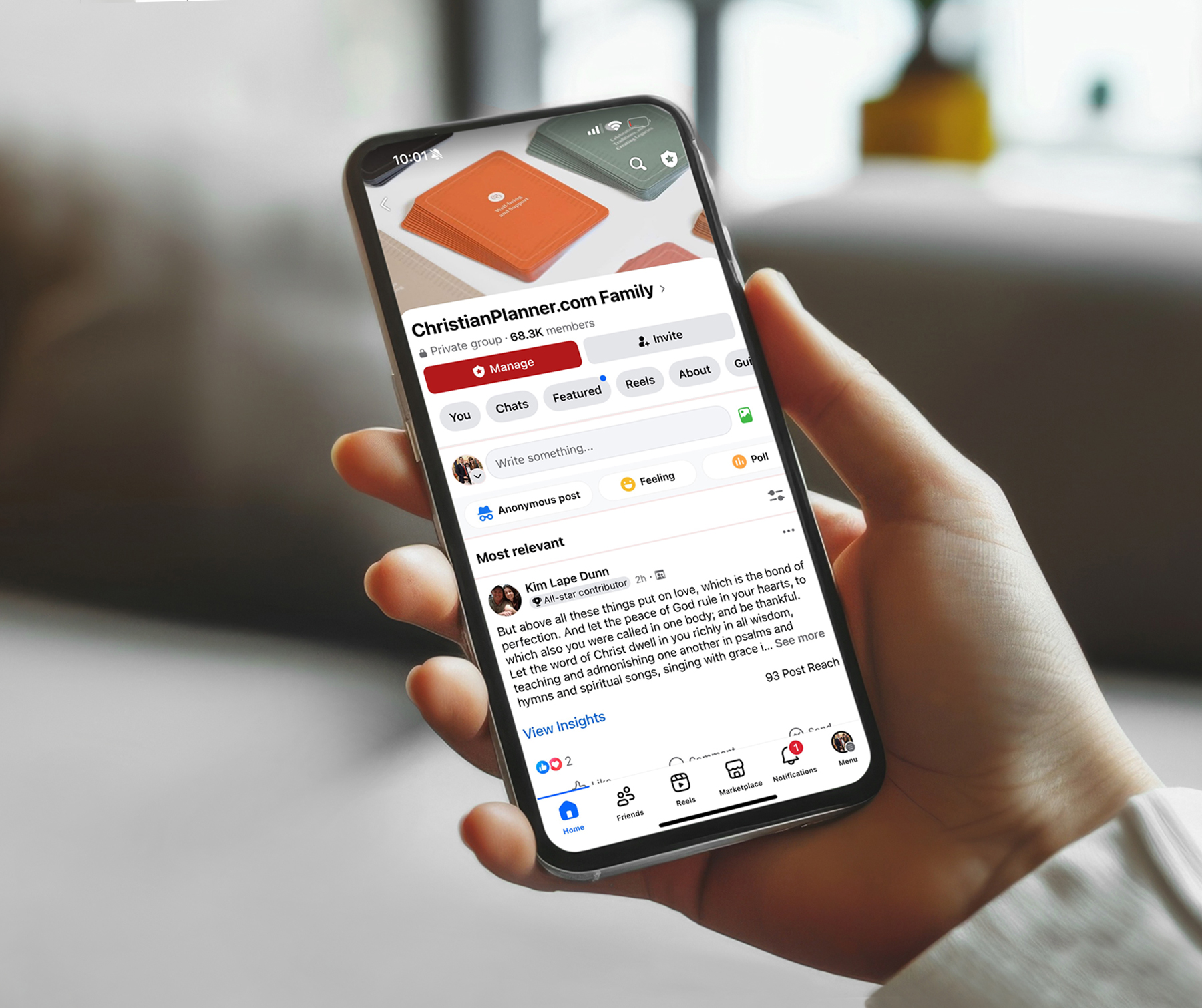 Person holding a smartphone displaying a social media group page.