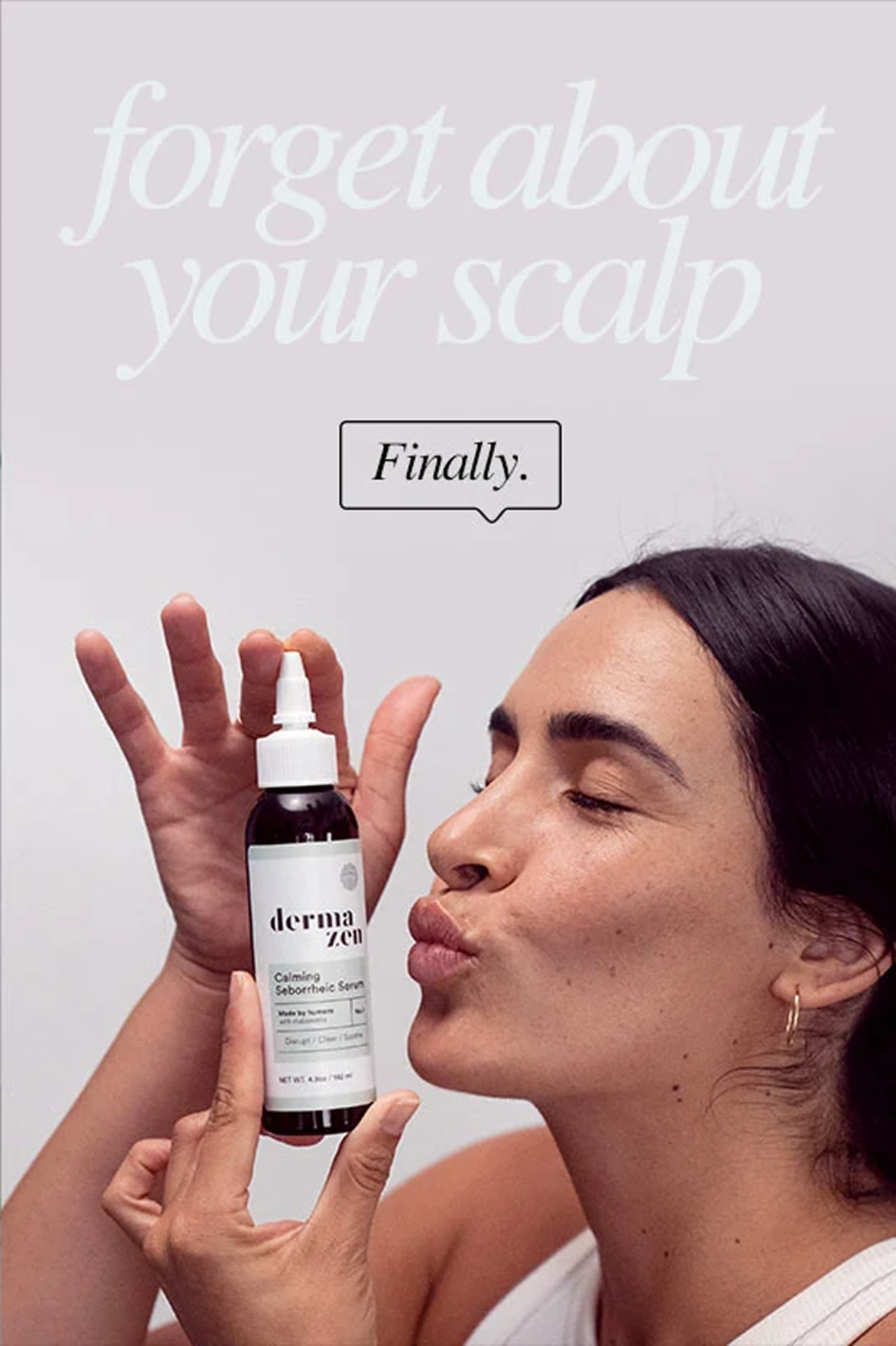 A woman with dark hair puckers her lips to kiss a bottle of Derma Zen scalp serum.