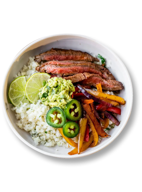 Bowl with sliced steak, rice, guacamole, lime, jalapeños, and bell peppers.