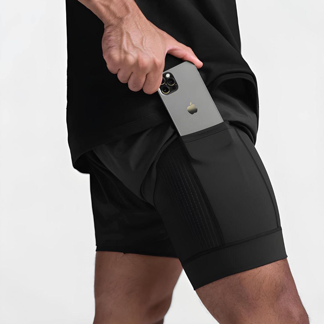 Person placing a smartphone in black athletic shorts pocket.