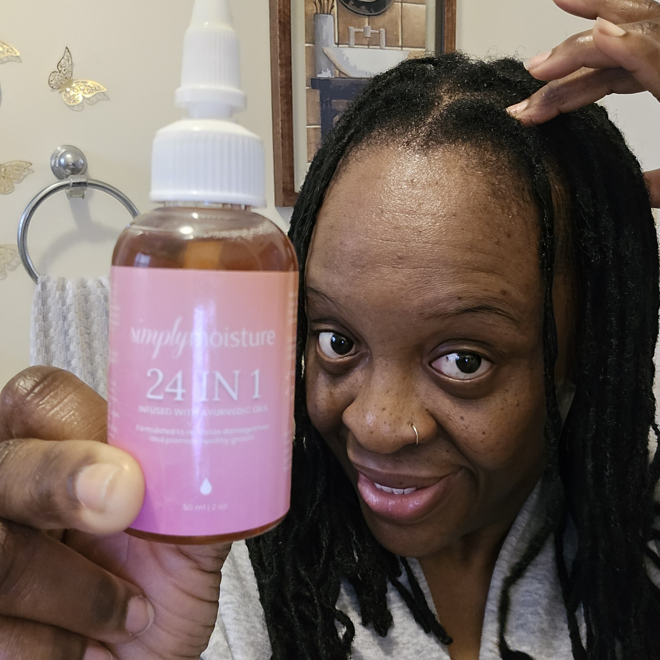 Person holding a bottle of hair product labeled '24 IN 1' with a smile.