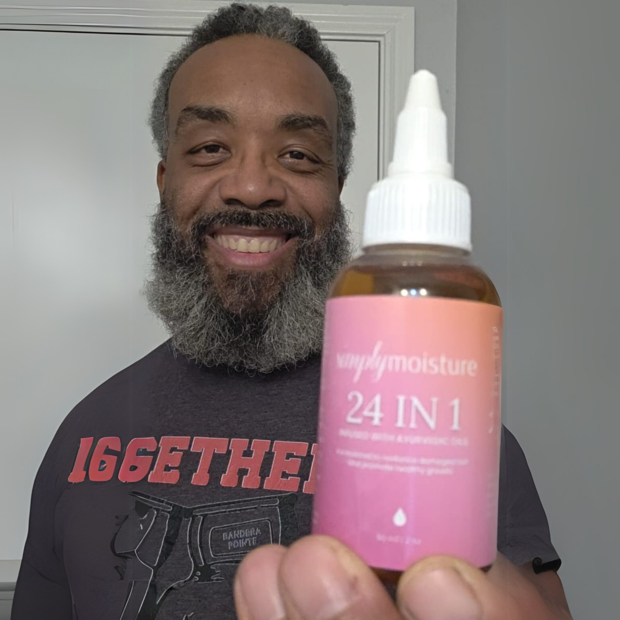 Person smiling, holding a bottle labeled '24 IN 1' with a pink label.