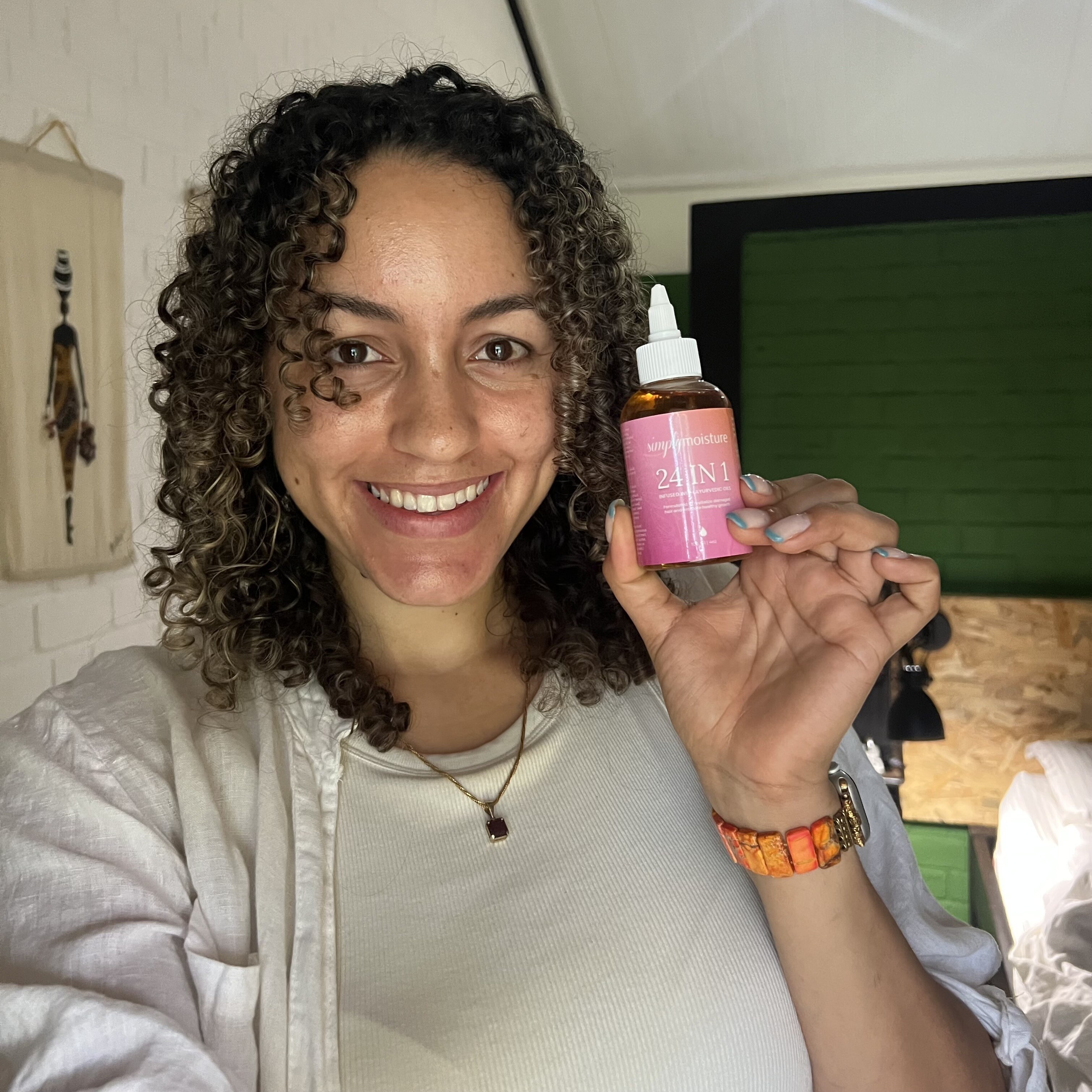 Person smiling and holding a bottle with a pink label.