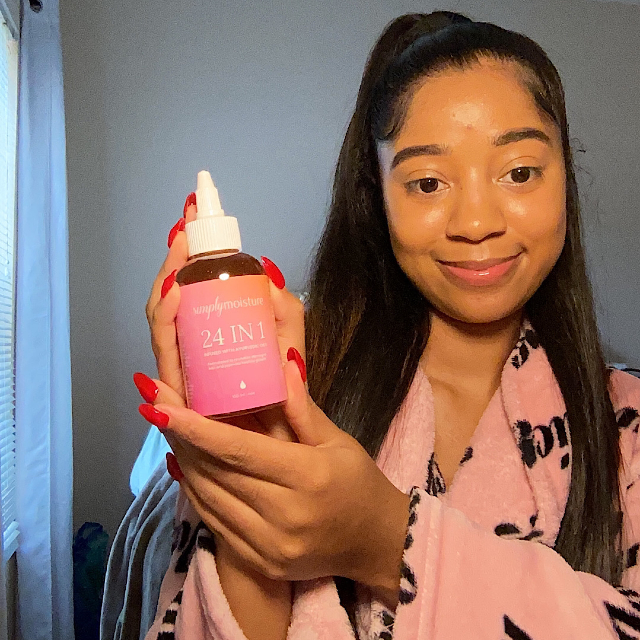 Person in a pink robe holding a bottle labeled '24 IN 1' with red nails.