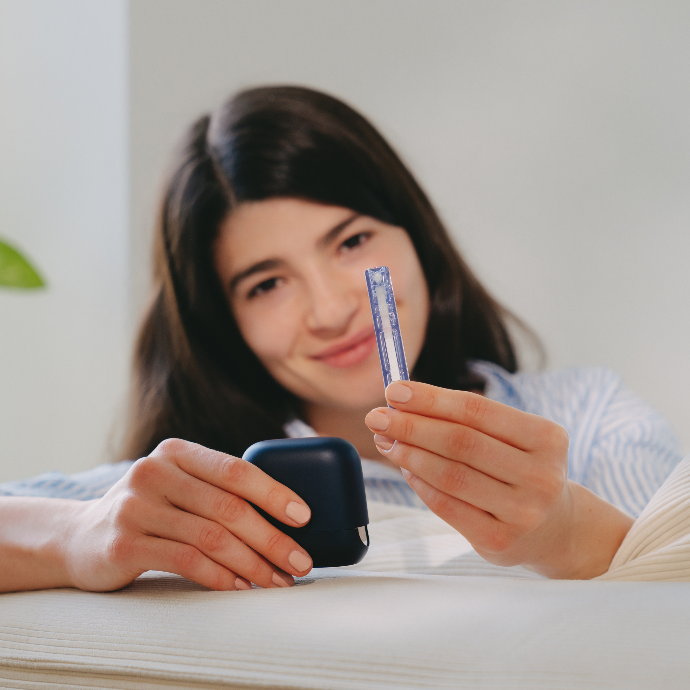 Woman holding a small blue case and a blue object, smiling.