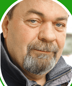 Portrait of a man with a beard and blue eyes, wearing a gray jacket.
