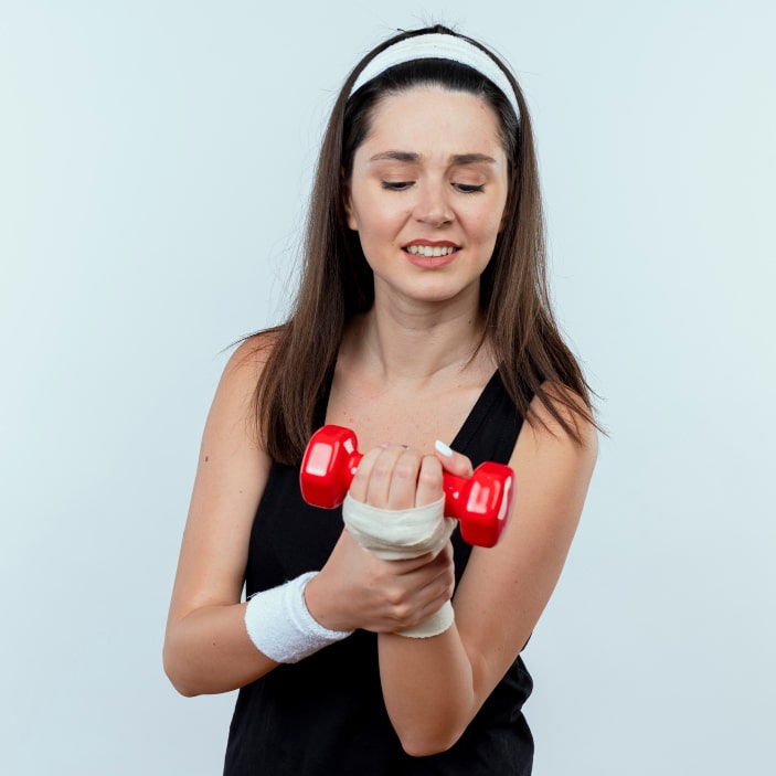 Woman in workout attire holding a red dumbbell with a bandaged wrist.