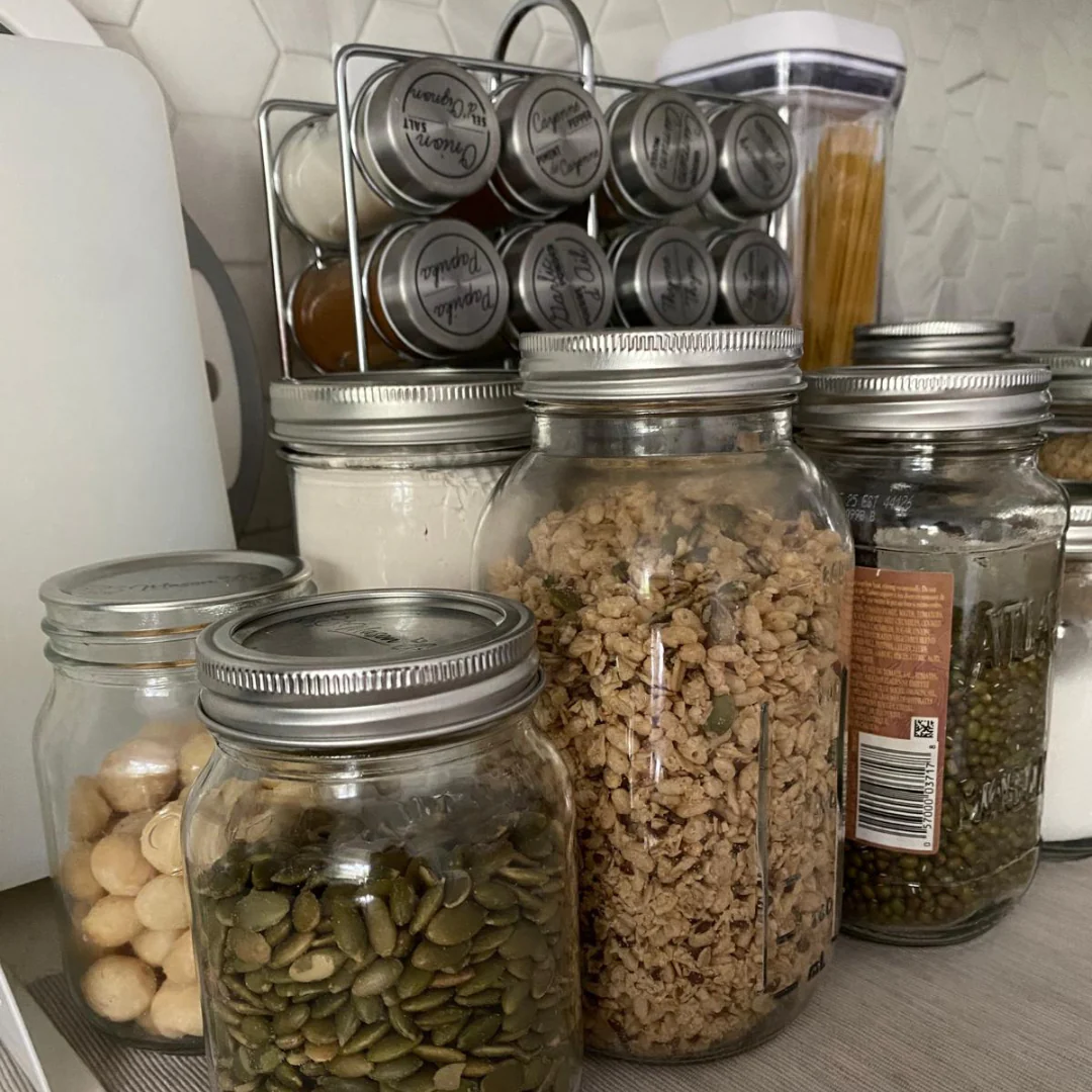 Jars of grains, seeds, and spices on a kitchen counter.
