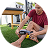 Person using a massage device on their leg while sitting on grass.