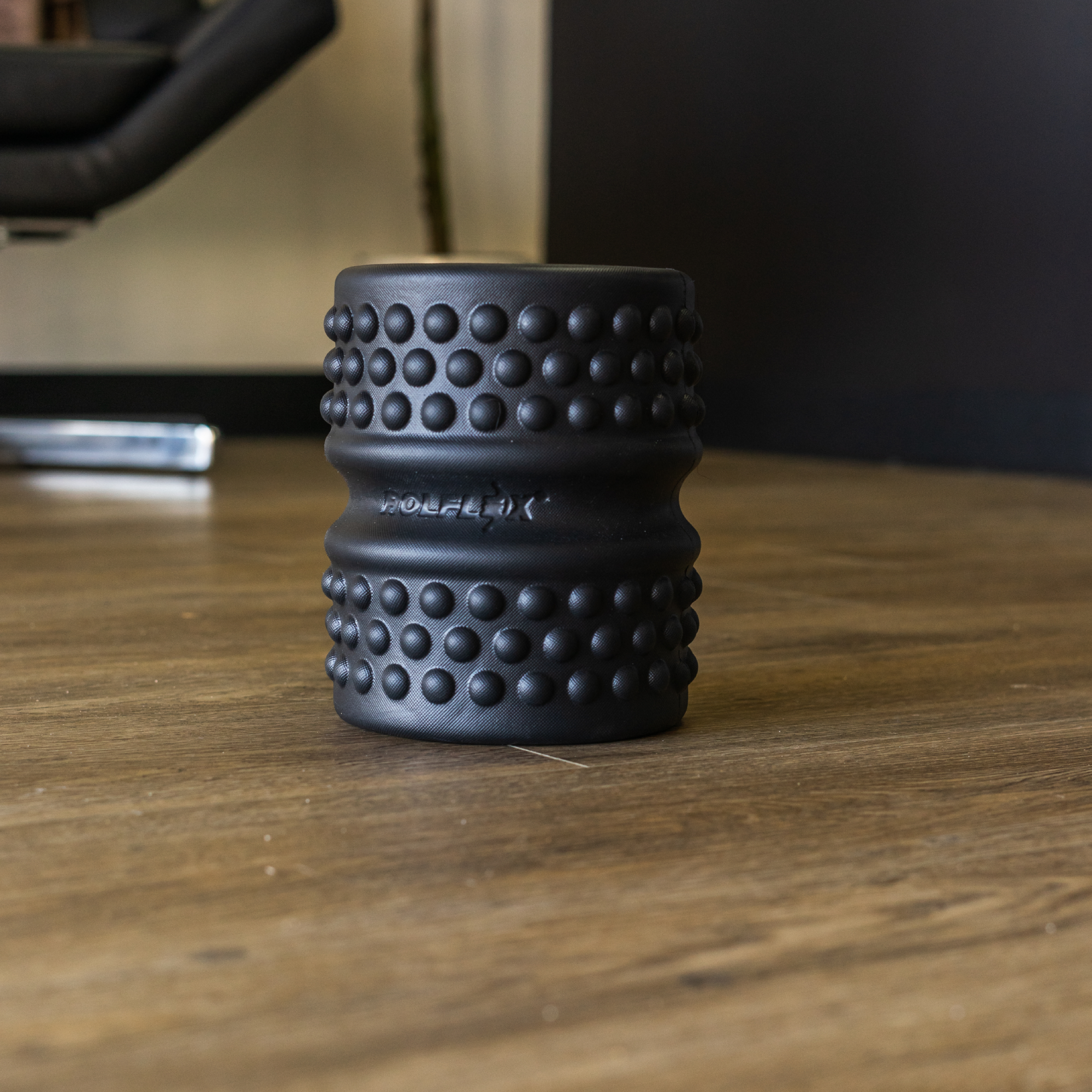 Person using a RolFlex massage tool on their arm with product packaging nearby.