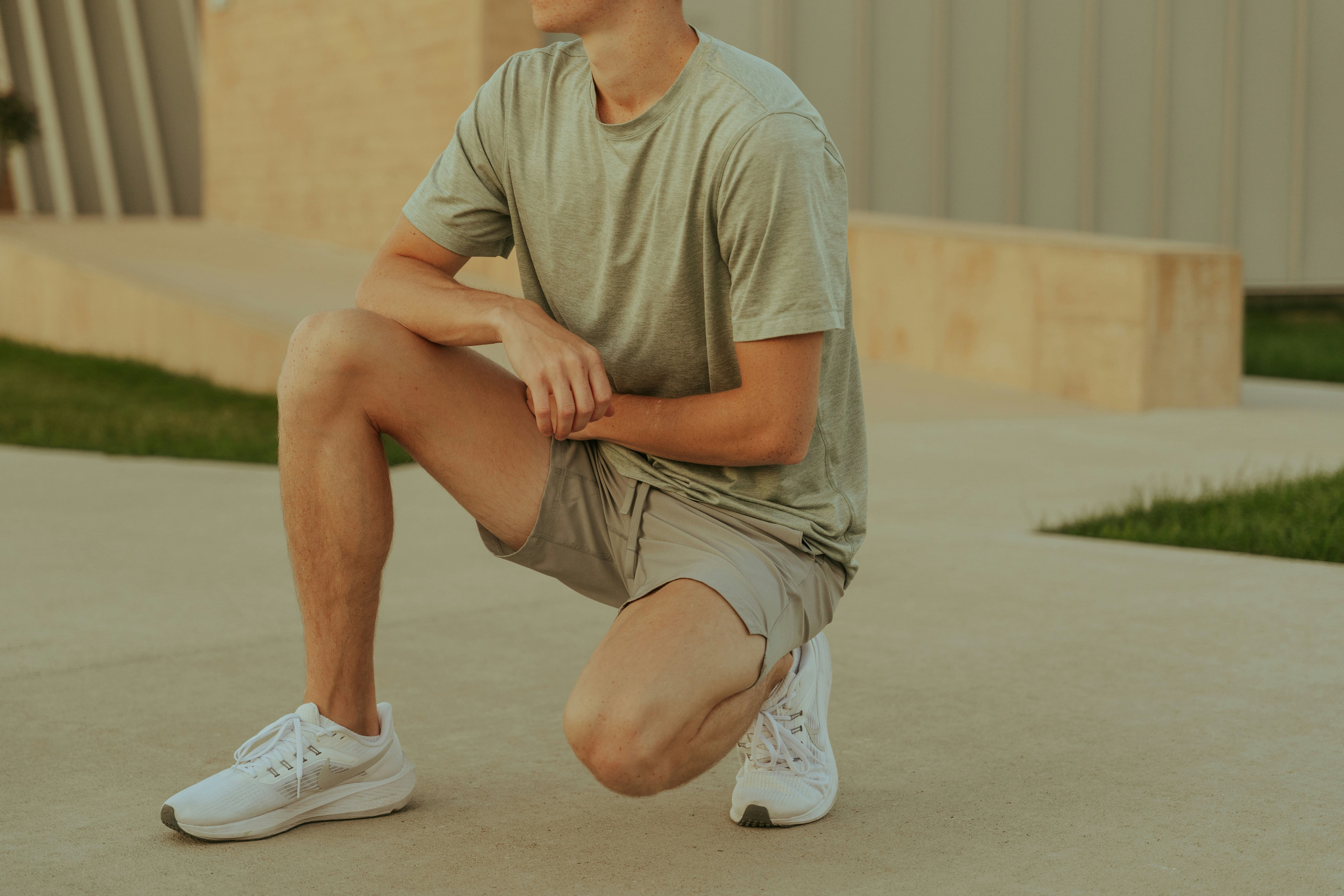 Person in casual attire kneeling outdoors on a concrete surface.