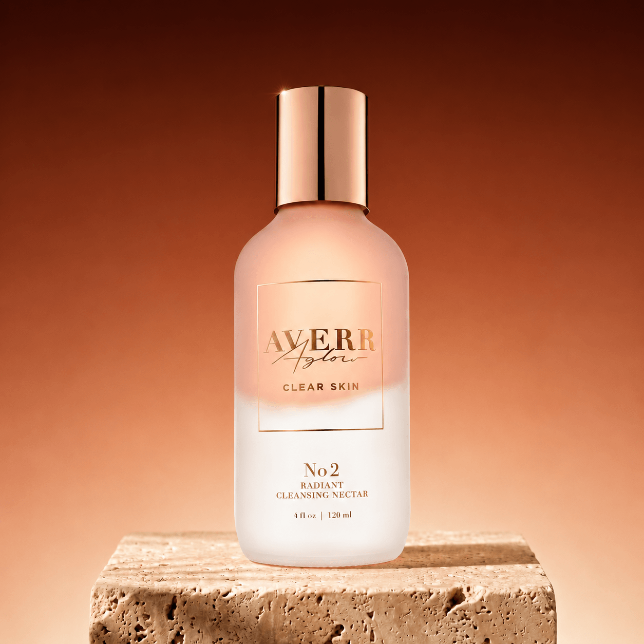 A bottle of Averr Aglow Radiant Cleansing Nectar with a rose gold cap on a stone pedestal.