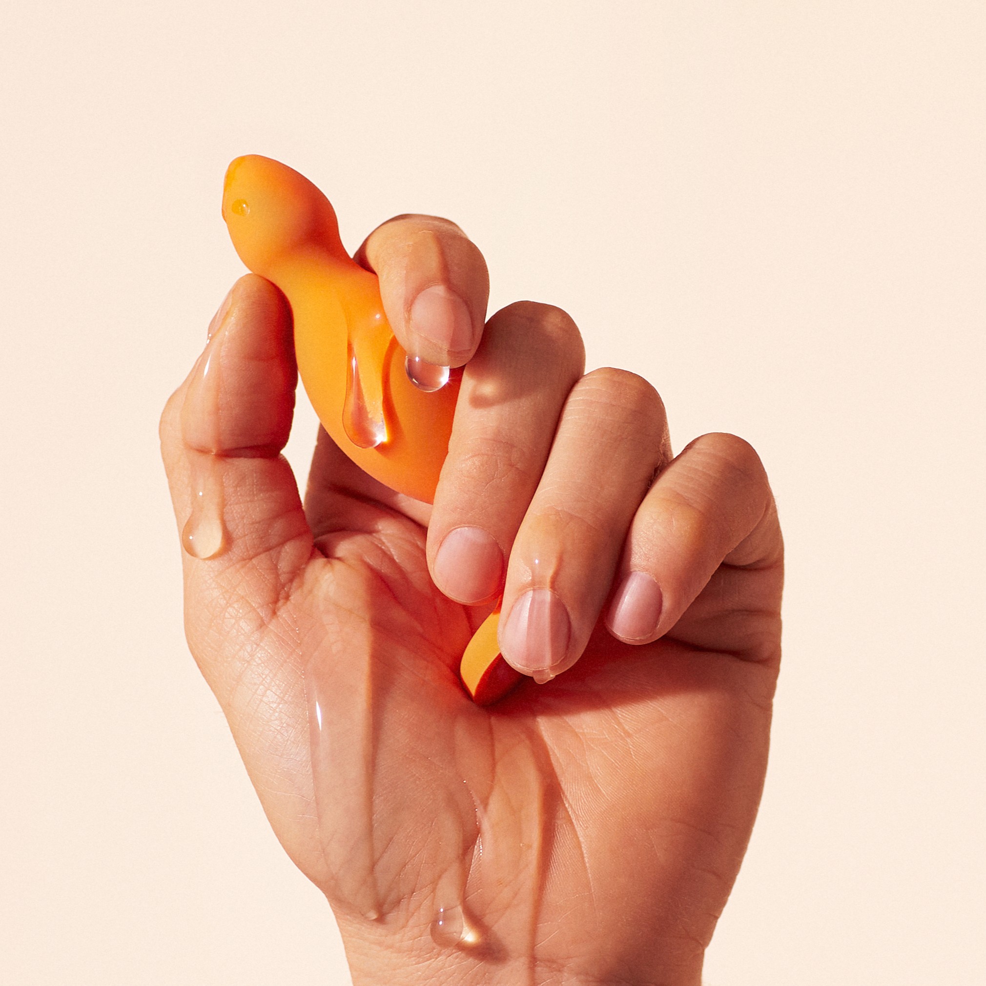 Hand holding an orange object with water droplets.