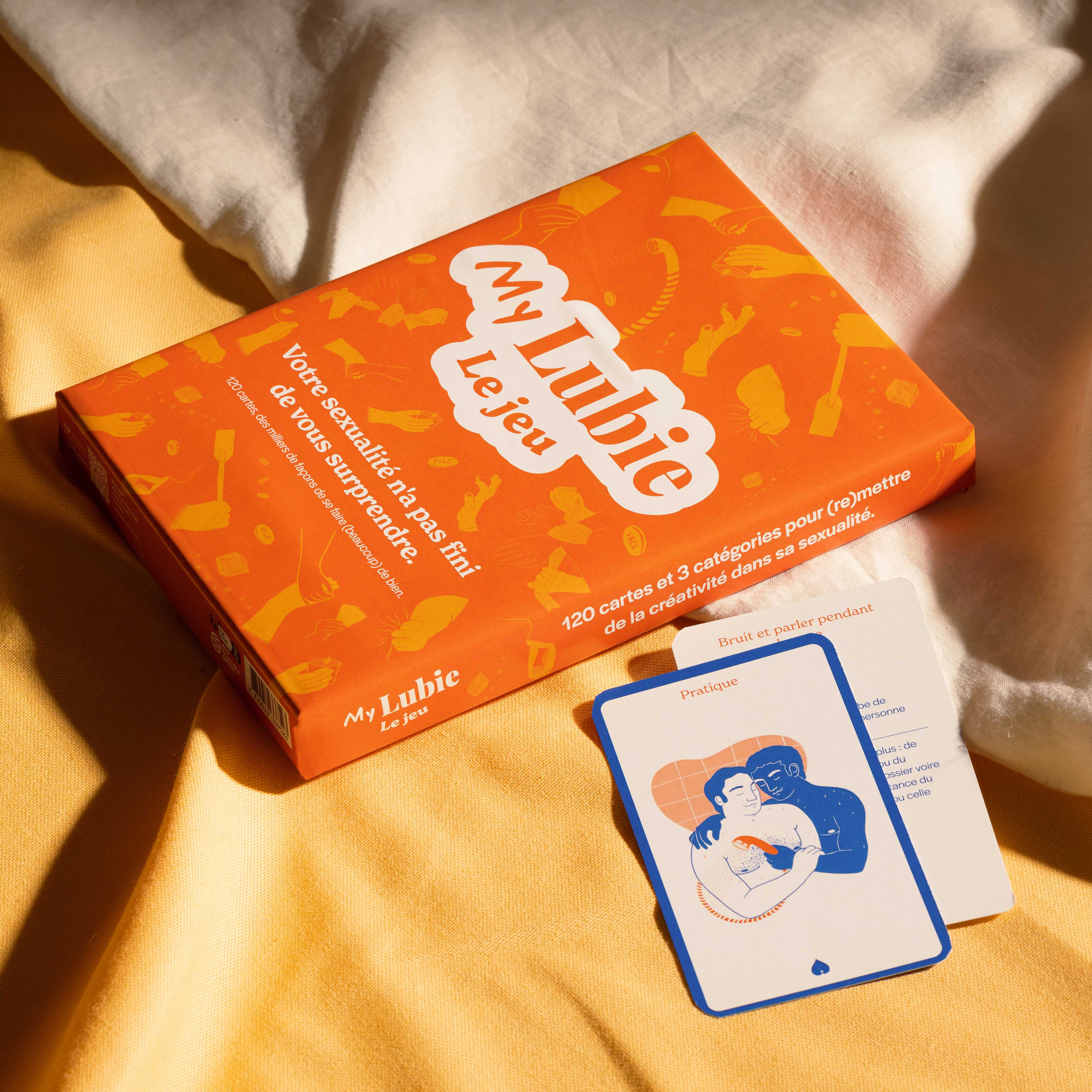 Orange box of 'My Lubie' game with cards on a yellow and white fabric.