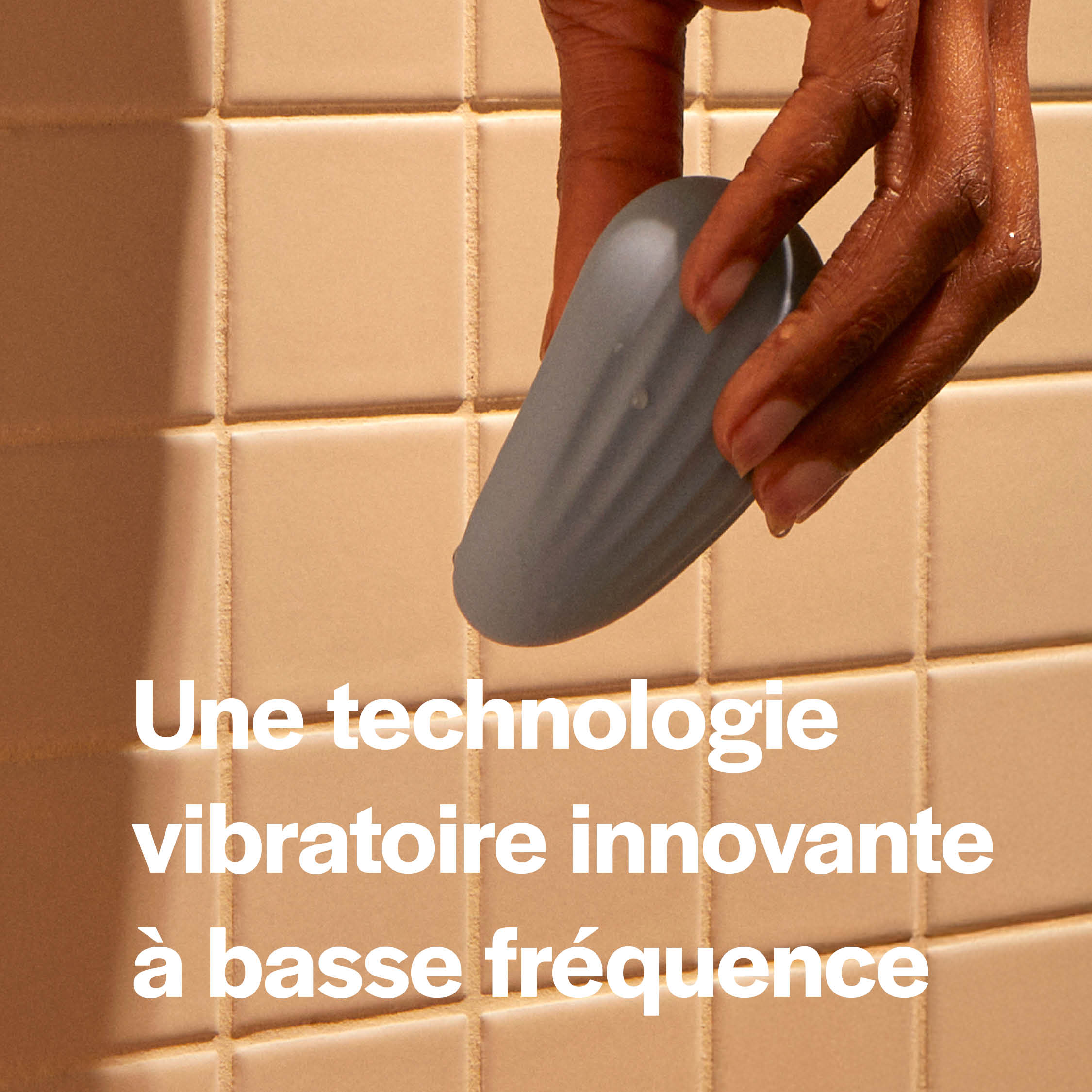 Hand holding a blue object against a tiled wall with French text overlay.