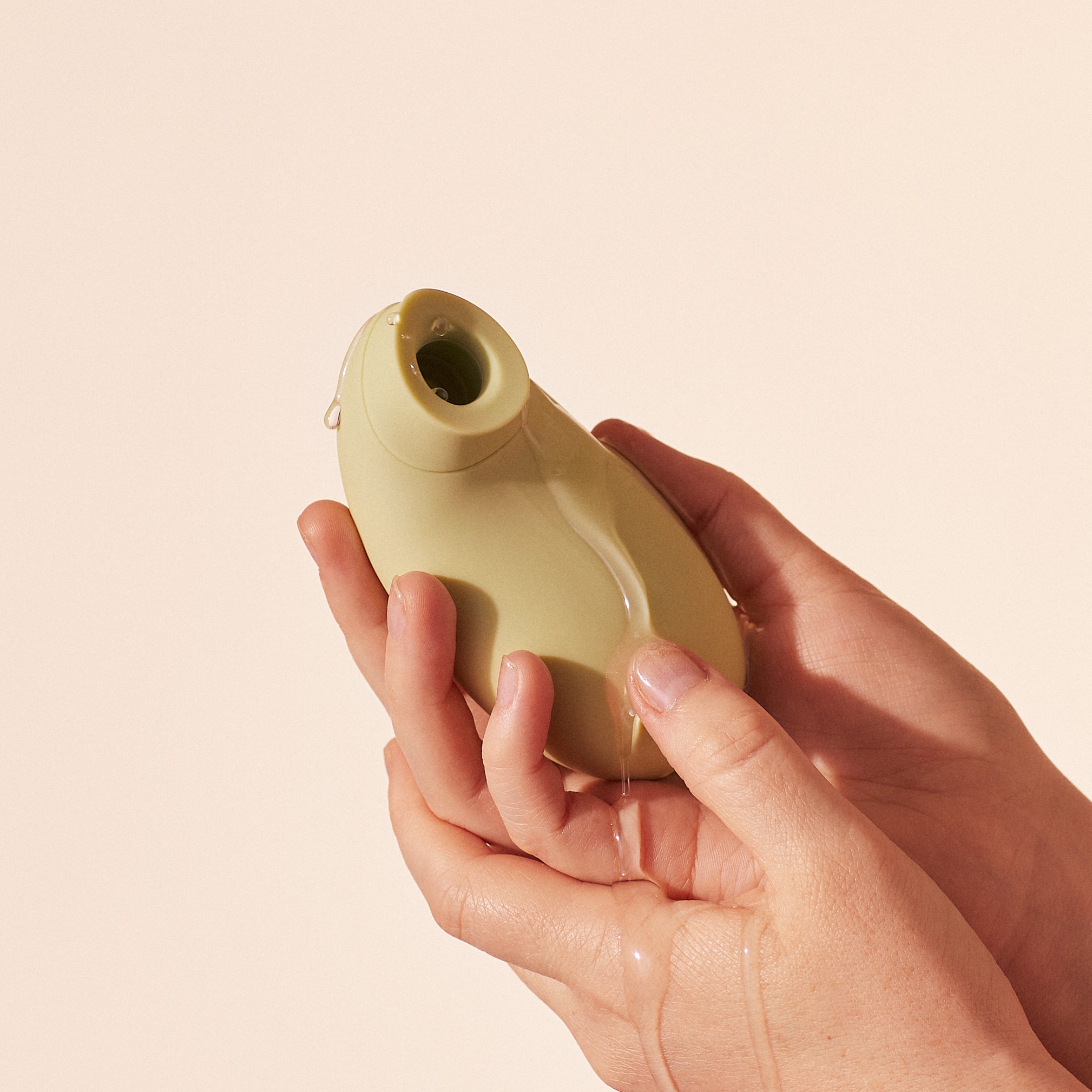 Hands holding a green object with liquid dripping.