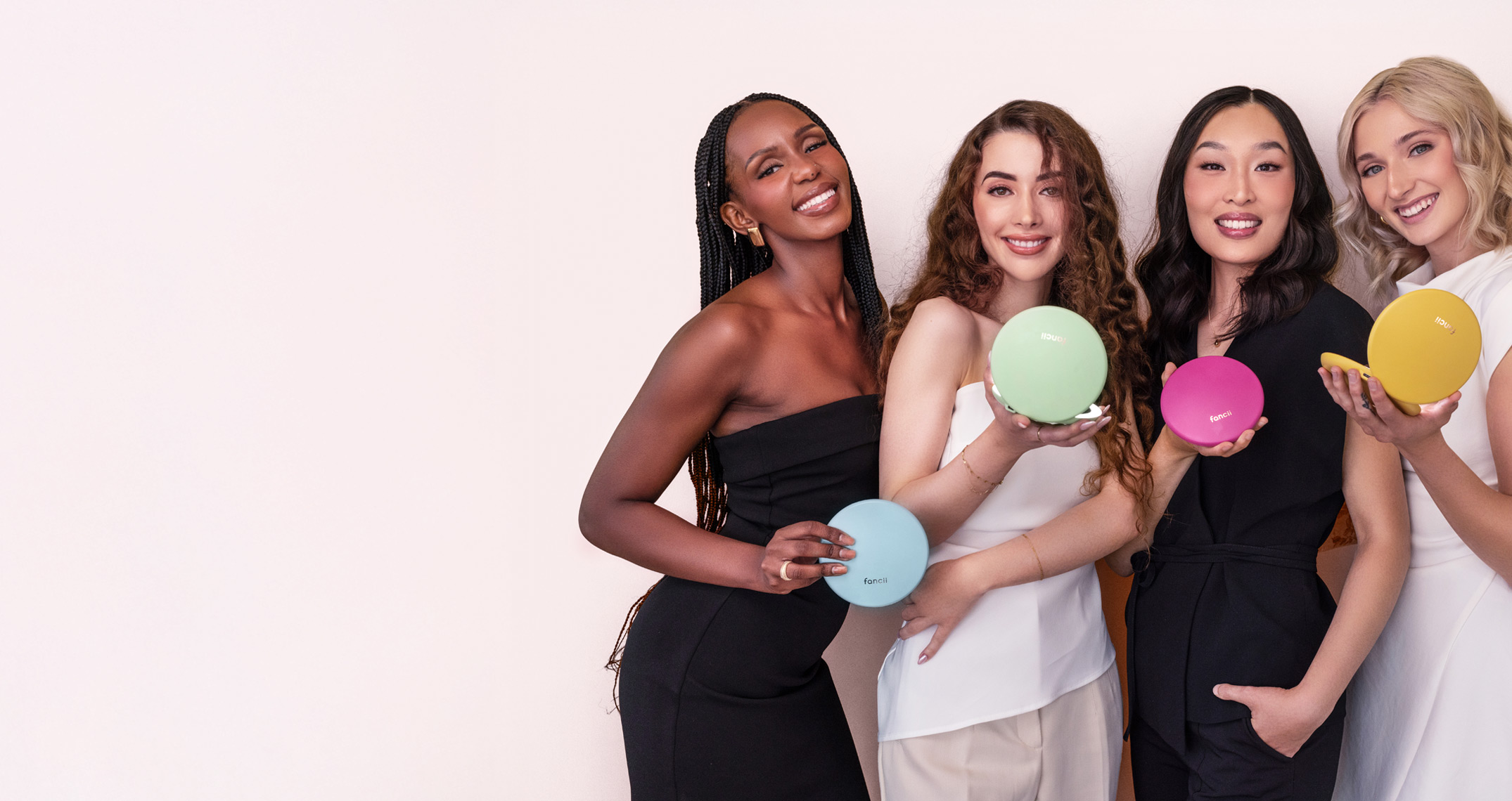 Four women smiling, holding colorful round objects against a light background.