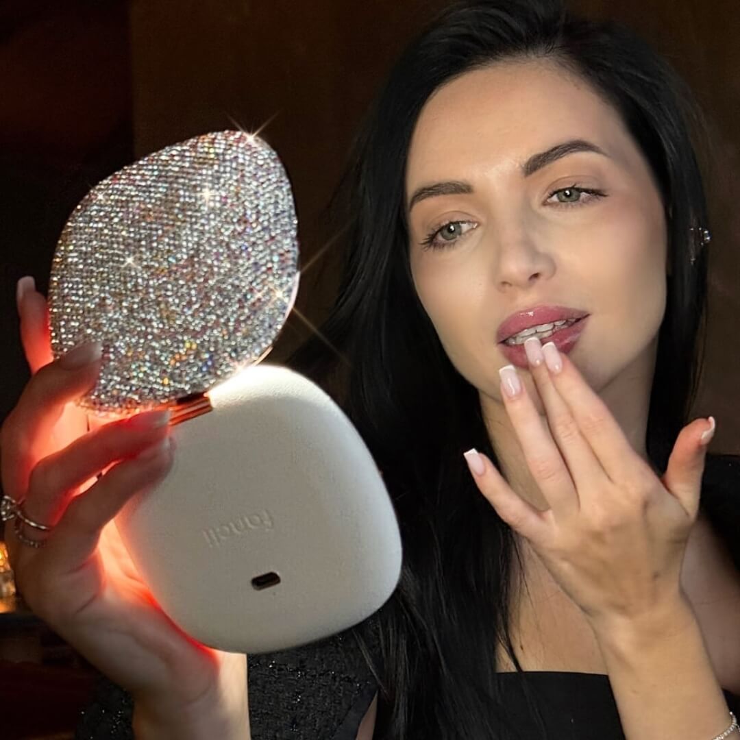 Person applying makeup using a sparkling hand mirror.