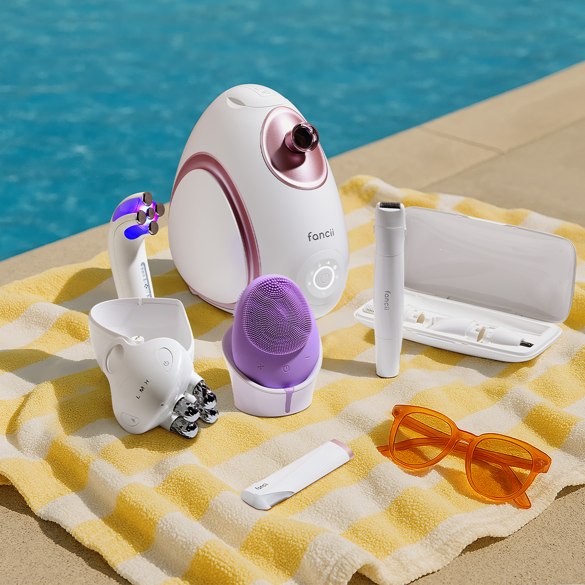 Assorted beauty devices on a yellow-striped towel by a pool.