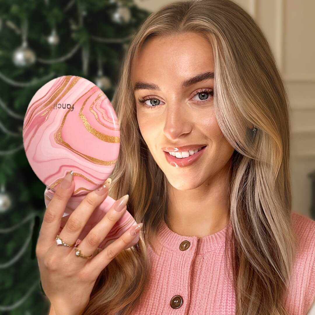 Woman in pink holding a pink marble-patterned hand mirror.