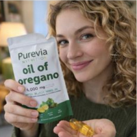 A smiling woman holds a pouch of Purevia Nutrition oil of oregano and a gel capsule.