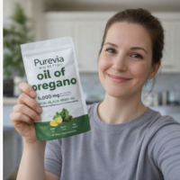 A smiling woman holds up a white pouch of Purevia Nutrition oil of oregano supplement.