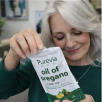 A woman with gray hair opens a white pouch of Purevia Nutrition oil of oregano.