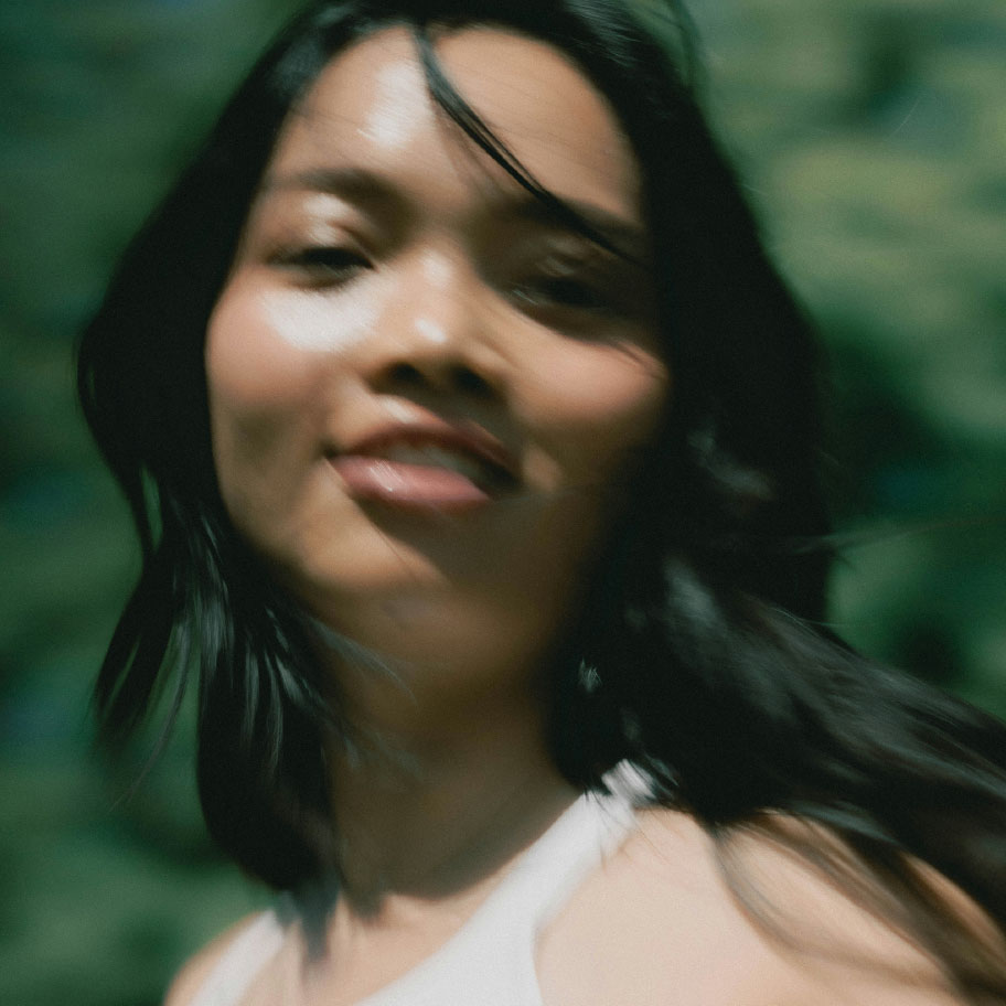 A blurry close-up photo of a smiling woman with dark hair, with her head in motion.