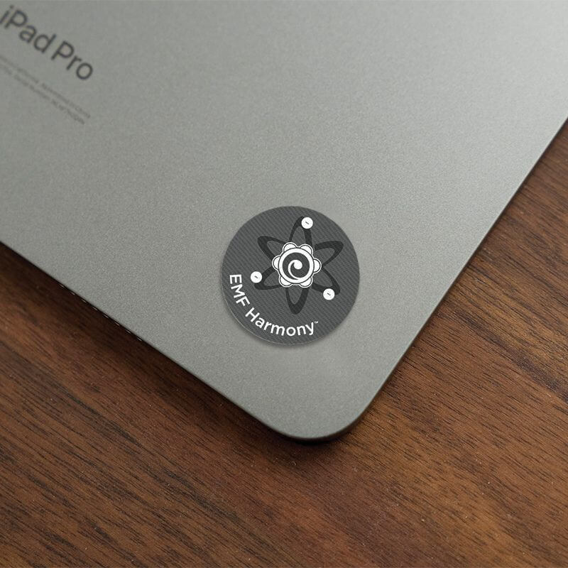 Close-up of an iPad Pro with an EMF Harmony sticker on a wooden surface.