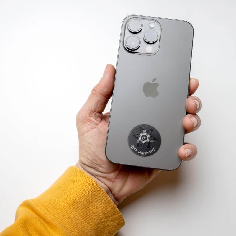 Hand holding a smartphone with a sticker on the back.