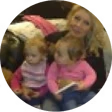 A woman sitting with two young children on her lap.